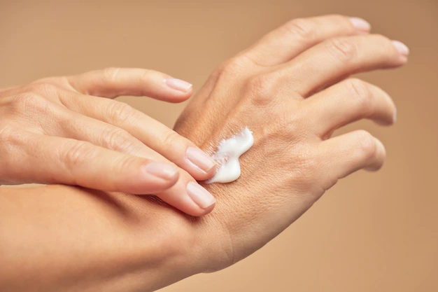 Female hands applying hand cream